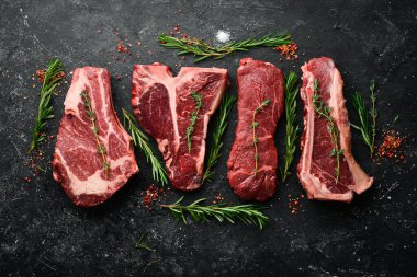 Çiğ siyah Angus Prime bifteği: T-bone, striploin, Rib, New York bifteği. Üst Manzara. Taş bir arka planda.
