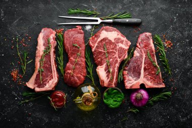 Çiğ siyah Angus Prime bifteği: T-bone, striploin, Rib, New York bifteği. Üst Manzara. Taş bir arka planda.