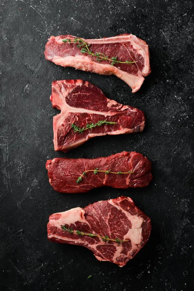 Çiğ siyah Angus Prime bifteği: T-bone, striploin, Rib, New York bifteği. Üst Manzara. Taş bir arka planda.