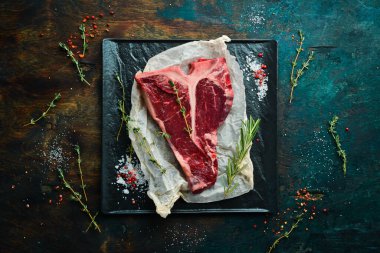 Kekik, biberiye ve baharatlı bir taş masada çiğ biftek. Üst Manzara. Siyah taş kesme masasının üstünde düz bir görünüm vardı..