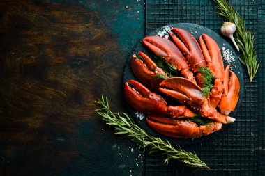 Baharatlı kırmızı ıstakoz pençeleri ve siyah taş tabakta maydanoz. Siyah bir arka planda. Kırsal tarzda. Deniz ürünleri lezzetleri..
