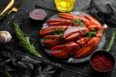 Baharatlı kırmızı ıstakoz pençeleri ve siyah taş tabakta maydanoz. Siyah bir arka planda. Kırsal tarzda. Deniz ürünleri lezzetleri..