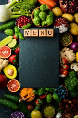 Sağlıklı beslenme konsepti: Siyah taş arka planda sebze ve meyveler. Üst Manzara. Metnin için boş yer.