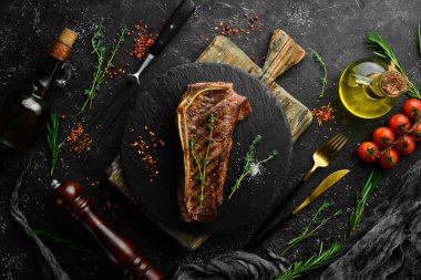 Kemiklerde ızgara New York bifteği, baharatlar ve otlar. Sulu pişmiş biftek. Üst Manzara. Kırsal tarzda. Düz Yat.