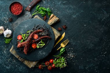 Sarımsak sosunda pişirilmiş ahtapot dokunaçları ve mürekkepbalıklı kara makarna. Lüks restoran yemekleri. Deniz ürünleri. Kırsal tarzda. Düz Yat.