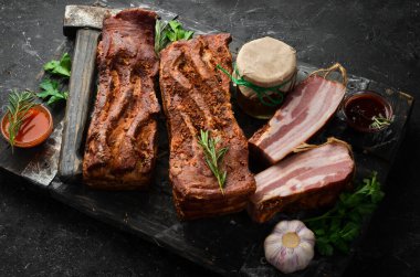 Baharatlı füme domuz pastırması. Siyah bir arka planda tütsülenmiş et parçası. Üst görünüm.