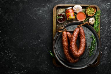 Ev yapımı füme sosis yüzüğü. Siyah taştan bir arka planda sosis. Üst görünüm.