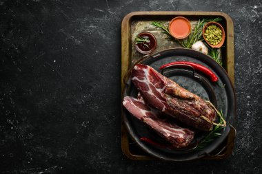 Kurutulmuş ve tuzlanmış et. Prosciutto, Jamon, siyah taşlı arka planda. Üst Manzara. Metin için boş alan.