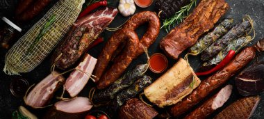 Et pankartı. Tütsülenmiş et, sosis, salam ve kurutulmuş et. Siyah taştan bir arka planda.