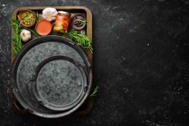 Yemek arkaplanı. Metal tepside sebzeler, baharatlar ve aromatik otlar. Siyah taştan bir arka planda.