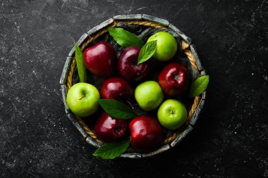 Tepside kırmızı ve yeşil elma seti. Kırsal tarzda. Siyah taştan bir arka planda.