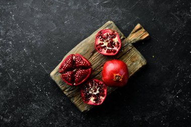 Birkaç olgun nar meyvesi ve ahşap ahşap arka planda eski bir kesim tahtasının üzerinde nar yapraklı açık bir nar..