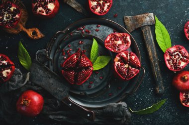 Koyu ahşap arka planda, yaprağın yanında olgun nar meyvesi. Metnin için boş yer.