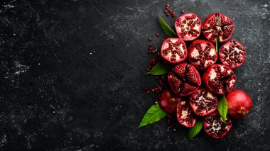 Koyu ahşap arka planda, yaprağın yanında olgun nar meyvesi. Metnin için boş yer.