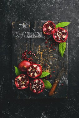 Koyu ahşap arka planda, yaprağın yanında olgun nar meyvesi. Metnin için boş yer.