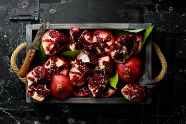 Yapraklı sağlıklı nar meyvesi ve tahta bir kutuda açık nar. Üst görünüm.