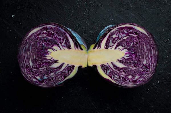 Fresh cabbage. Fresh sliced purple cabbage. On a black stone background.