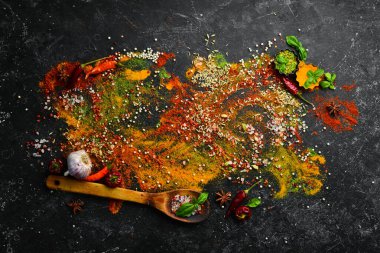 Siyah taş bir arka planda baharat ve baharatlar dizisi. Üst görünüm.