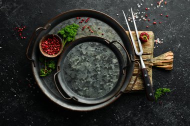 Siyah taş pişirme arka planı. Metal tepsi, baharatlar ve sebzeler. Üst Manzara. Metnin için boş yer.