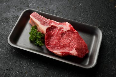 Kemiğin üzerinde taze taze biftek. Siyah taştan bir arka planda. Organik yiyecekler.