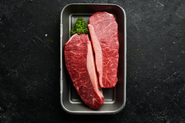 Siyah taştan bir arka planda çiğ biftek. Üst Manzara. Çiğ et.