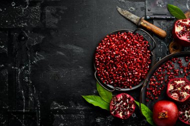 Tabakta olgun nar tohumları var. Taze nar meyvesi. Siyah taştan bir arkaplanda Üst görünümde.