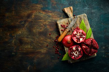 Koyu ahşap arka planda, yaprağın yanında olgun nar meyvesi. Metnin için boş yer.