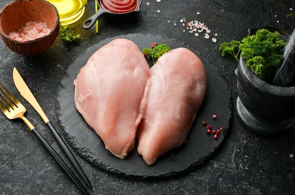 Chicken meat. Raw fresh chicken breast on black slate stone background. Top view. Raw meat.