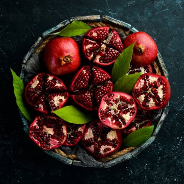 Yapraklı sağlıklı nar meyvesi ve tahta bir kutuda açık nar. Üst görünüm.