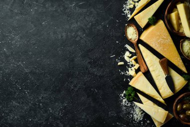 Siyah taşlı arka planda peynir bıçaklı sert peynirler. Parmesan peyniri. Üst Manzara. Metnin için boş yer.