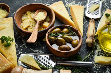 Dairy products. Parmesan cheese, olives and snacks on a stone table. Top view. On a concrete background.