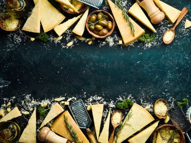 Dairy products. Parmesan cheese, olives and snacks on a stone table. Top view. On a concrete background.