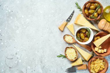 Cheese background. Set of hard cheeses, olives, rosemary and spices. Hard parmesan cheese. Top view. On a stone background.