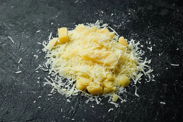 Grated parmesan cheese. Cheese. Top view. On a black stone background.