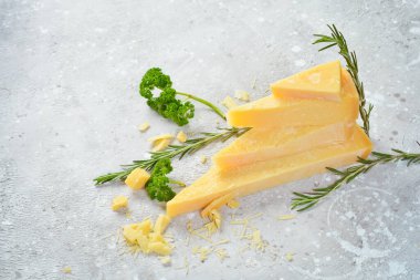 Parmesan cheese cut into pieces. Cheese. Side view. On a gray stone background.
