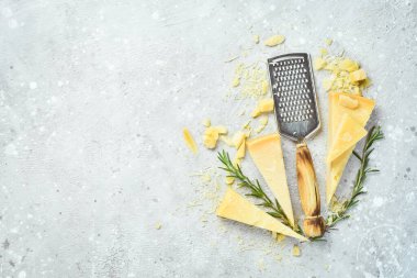 Cheese grater and hard parmesan cheese against a gray stone background. Food background. Free space for text.