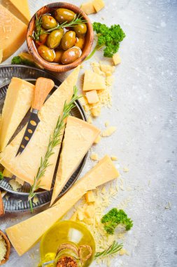 Pieces of hard cheese and olives on a gray stone background. Food background. Free space for text.