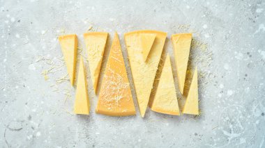 Cheese background. Triangular pieces of hard cheese on a stone background. Parmesan. Free space for text.