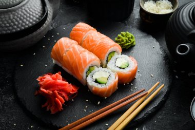 Sushi roll (Philadelphia) with salmon, avocado, cream cheese on a black background. Sushi menu. Japanese food.
