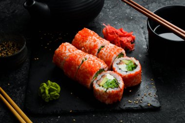 Traditional delicious sushi rolls with caviar. Traditional Japanese food. On a black stone plate.