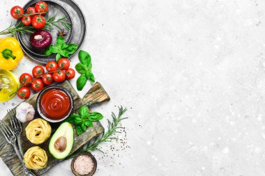 Frame of organic food. Fresh raw vegetables with spices, basil and rosemary on a gray stone background. Top view. Free space for text.