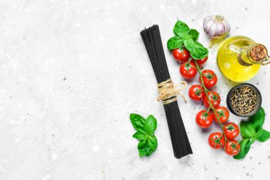 Gri taşlı arka planda taze fesleğenli kuru siyah spagetti. Kuru makarna. Üst Manzara. Metin için boş alan.