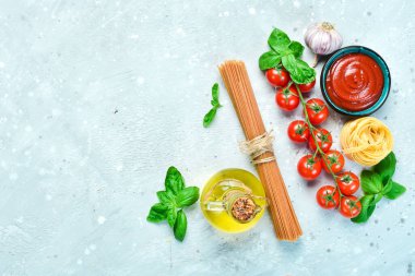 Gri taşlı arka planda taze fesleğenli kuru spagetti. Kuru makarna. Üst Manzara. Metin için boş alan.