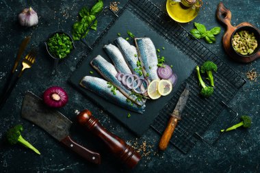 Siyah taş tabakta soğan ve baharatla tuzlanmış ringa balığı. Üst Manzara. Taş bir arka planda.