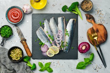 Siyah taş tabakta soğan ve baharatla tuzlanmış ringa balığı. Üst Manzara. Taş bir arka planda.