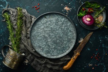 Baharat ve mutfak aletleriyle dolu karanlık mutfak masası. Siyah taştan bir arka planda.