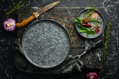 Baharat ve mutfak aletleriyle dolu karanlık mutfak masası. Siyah taştan bir arka planda.