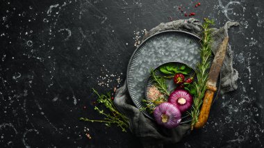 Baharat ve mutfak aletleriyle dolu karanlık mutfak masası. Siyah taştan bir arka planda.