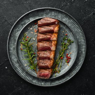 Baharatlı ızgara mermer biftekler. Siyah taştan bir arka planda.