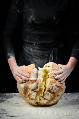 Kadınların elinde kokulu beyaz ekmek. Kara un pişirme arkaplanı.